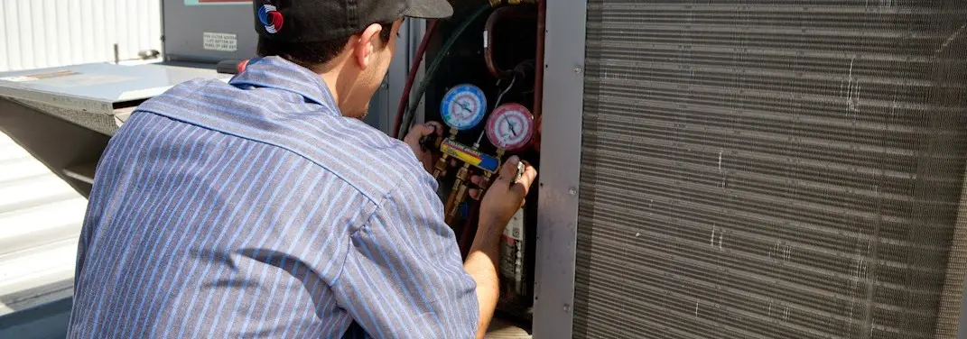 HVAC technician servicing a condenser unit in Oakton